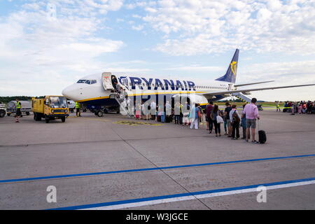 MEMMINGEN, Germania - 6 Luglio 2019: persone imbarco irlandese Ryanair compagnia aerea low-cost aereo Boeing 737 con sfondo con cielo nuvoloso su luglio 6, 2019 in Memmin Foto Stock