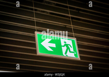 Emergency fire exit segno verde brillante in oscurati background in aeroporto Foto Stock