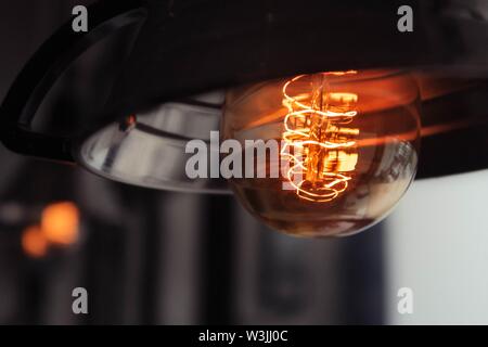 Primo piano di una grande lampadina illuminata con una luce sfocata sfondo Foto Stock