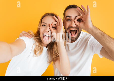 Immagine della coppia gioiosa allegria e spuntavano le linguette mentre mostra ok firmare insieme isolate su sfondo giallo Foto Stock