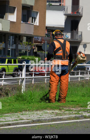 Lavoratore di sesso maschile il taglio di prato utilizzando electric rasaerba. Foto Stock