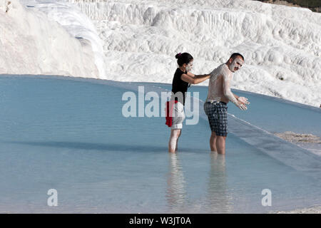 Bagnanti godono di sfregamento del minerali ricchi di fango su ogni altri corpi in una delle piscine termali all'travertini (Castello di Cotone) a Pamukkale, Turchia. Foto Stock