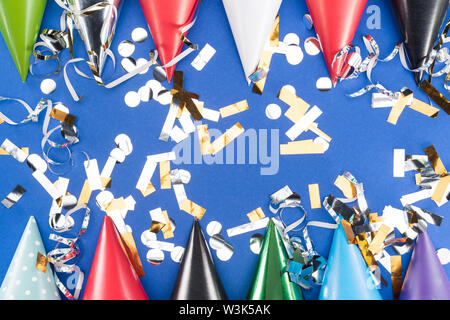 Festa colorati cappelli e coriandoli argento su sfondo blu Foto Stock