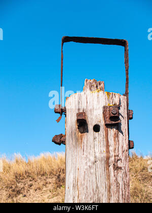 Un palo di legno con raccordi arrugginito che assomigliano a una faccia del robot Foto Stock