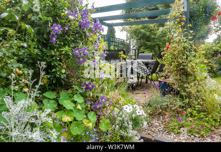 Tavolo e sedie sotto un pergolato di legno in un giardino cottage. Foto Stock