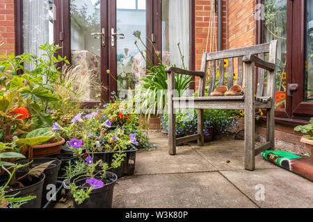 Una coppia di uomini sandali di cuoio su una sedia di legno in un angolo di un giardino. Foto Stock