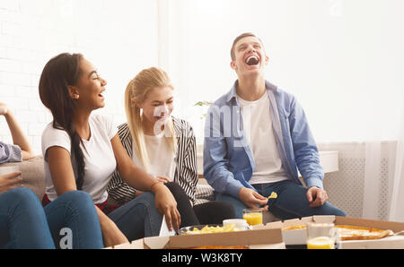 Teen amici avente home partito, mangiare la pizza Foto Stock