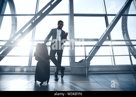 Imprenditore Afro in piedi in aeroporto con Buggage Foto Stock