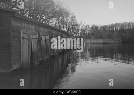 Vecchia Darsena di legno al lago nella nebbia mattutina, la fotografia in bianco e nero. Foto Stock