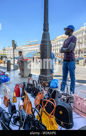 Immigrato counerfeit vendita merci sulle strade di Madrid vicino alla Puerta del Sol, centro di Madrid, Spagna. Foto Stock