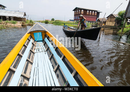 Maing Thauk, Myanmar - Aprile 2019: tradizionale birmana barca di legno andando attraverso Maing Thauk villaggio galleggiante al Lago Inle. Foto Stock