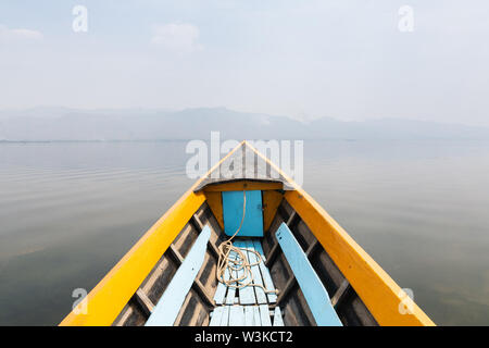 Barca di legno tradizionale naso con Lago Inle e le montagne sullo sfondo, Myanmar. Foto Stock