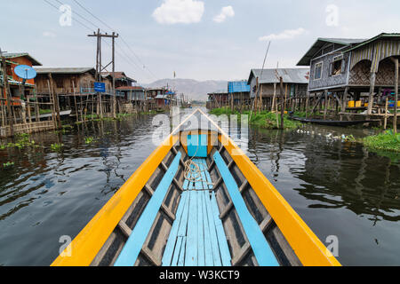 Maing Thauk, Myanmar - Aprile 2019: tradizionale birmana barca di legno andando attraverso Maing Thauk villaggio galleggiante al Lago Inle. Foto Stock