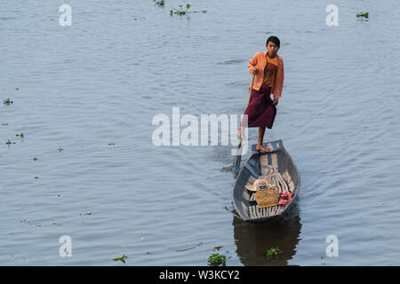 Nyaungshwe, Myanmar - Aprile 2019: uomo birmano gamba canottaggio in una barca di legno, il trasporto di cestelli per la cattura di lumache e pesce Foto Stock
