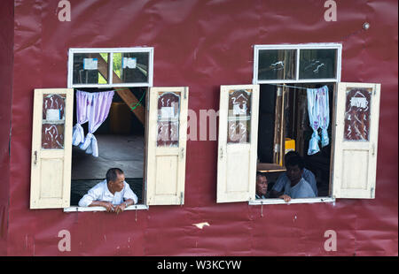 Maing Thauk, Myanmar - Aprile 2019: vecchio uomo birmano guardando fuori della casa galleggiante finestra. Foto Stock