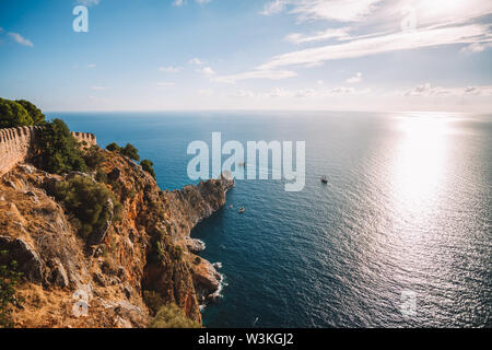 Alanya riva del mare con le vecchie mura del castello al di sopra di bel mare blu, Turchia, distretto di Antalya Foto Stock