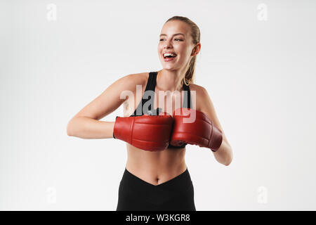 Immagine di adorabili e una forte donna che indossa tuta e guantoni da pugilato sorridente durante il combattimento isolate su muro bianco Foto Stock