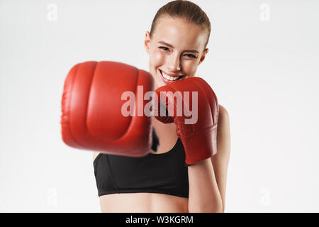 Immagine di incantevole donna forte indossare tuta e guanti da boxe punch facendo durante il combattimento isolate su muro bianco Foto Stock