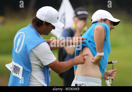 Caddy punti per un apparente morso sul nord irlandese Rory McIlroy (a destra) durante l'anteprima giorno tre del Campionato Open 2019 presso il Royal Portrush Golf Club. Foto Stock