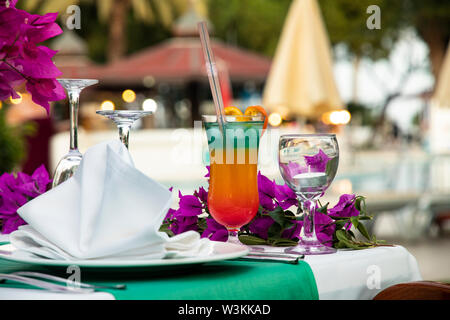 Bright multi-layered cocktail con una paglia su una tavola è servita per una vacanza. Cocktail party presso l'hotel sulla spiaggia. Il resto dal mare. Cena di gala Foto Stock