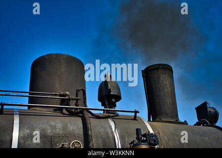 Una vista dettagliata di una storica nera locomotiva a vapore di soffiaggio arrugginito nero fumo fuori di un camino Foto Stock