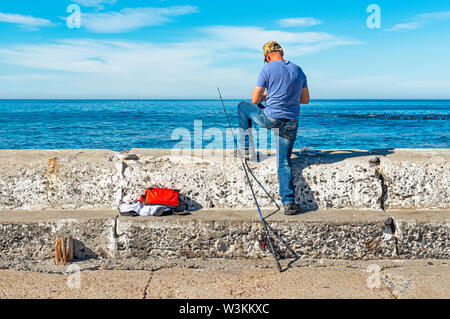 Pescatore nelle prime ore del mattino dal porto di Kalk Bay dall'Oceano Indiano vicino a Cape Town, Sud Africa. Foto Stock