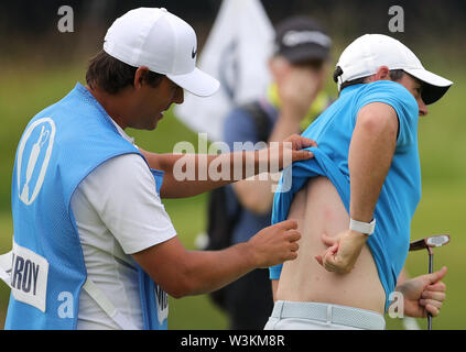 Caddy punti per un presunto morso sul nord irlandese Rory McIlroy (a destra) durante l'anteprima giorno tre del Campionato Open 2019 presso il Royal Portrush Golf Club. Foto Stock