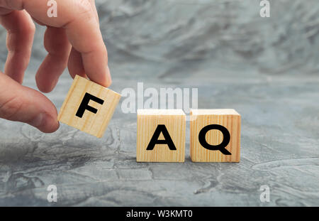 Mettendo mano cubo di legno blocco con word FAQ (domande frequenti). Raccolta di domande frequenti su qualsiasi argomento e risposte alle loro. Foto Stock