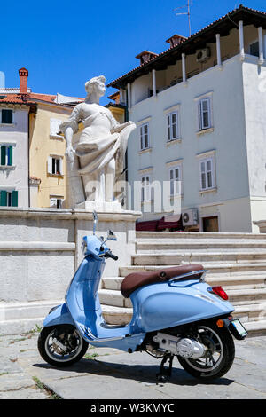 Blue scooter parcheggiata accanto alla statua in 1 maggio Square, pirano, Slovenia Foto Stock