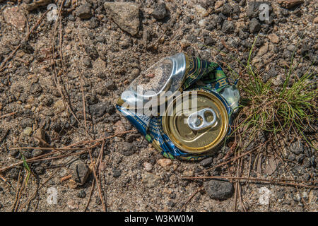 Una schiacciata di soda o lattina di birra la posa a terra vicino alla spiaggia al lago in una giornata di sole in estate Foto Stock