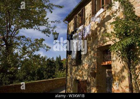 Via Gozzante, Pienza, Toscana, Italia: pezzata dalla luce del sole sulla parete e lavaggio Foto Stock