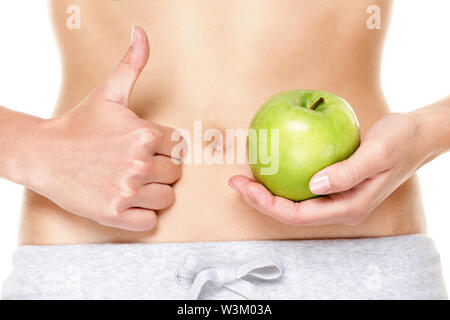 Mangiare Sano frutta mela è buona per lo stomaco la digestione e la salute. La donna che mostra mele verdi e il pollice alzato la mano in segno di close-up di stomaco pancia. Foto Stock