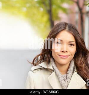 Autunno donna ritratto in caduta all'esterno. Bella multi-etnico girl Brunette con lunghi capelli scuri sorridendo felice guardando la fotocamera. Gara di Misto Asiatico Cinese / Caucasian modello femminile. Foto Stock