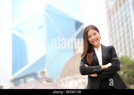 Giovani uomini d'affari asiatici business donna ritratto all'esterno. Imprenditrice sta eretta guardando la fotocamera in tuta. Multirazziale asiatica Cinese / caucasico professionale femminile in centro a Hong Kong. Foto Stock