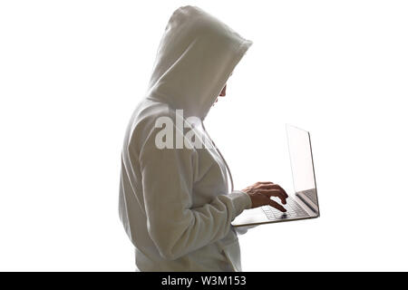 Una donna in una cappa è utilizzando un computer portatile. Hacker è utilizzando un computer portatile. Foto Stock