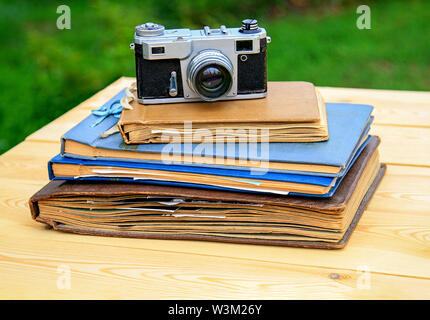 Il vecchio album di foto vecchia macchina fotografica su una luce tavolo in legno nel giardino estivo. Foto Stock