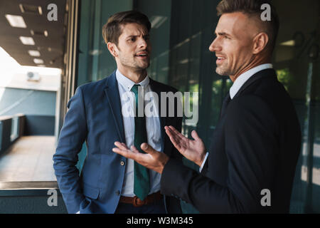 Immagine di disaccordo imprenditori partner vestito in abito formale a parlare e discutere di conflitto permanente, mentre al di fuori del centro di office Foto Stock