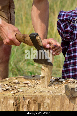 Uomo con ascia a forma di un cuneo di legno per essere usato nella suddivisione di un registro Foto Stock