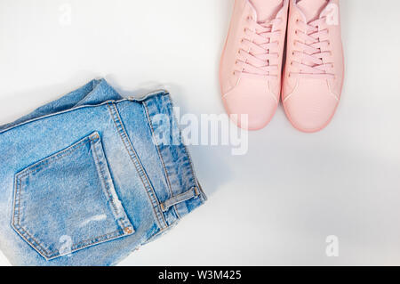 Composizione piana con una serie di vestiti, jeans e scarpe da ginnastica rosa. Vista dall'alto su uno sfondo bianco. Piatto, laici vista superiore Foto Stock