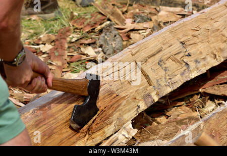 Uomo con ascia a forma di un registro di quercia in un fascio quadrato per uso in riproduzione medievale tradizionale Anglo Sassone con cornice in legno edificio Foto Stock