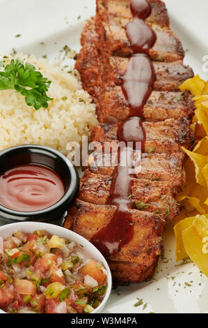 Barbeque costolette di maiale sulla piastra con riso e insalata vista ravvicinata Foto Stock