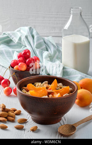 Muesli con albicocche e mandorle su bianco tavolo in legno Foto Stock