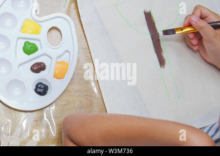 Vista superiore del bambino disegna le mani un gouache su carta. Gouache e carta per pittura e disegno del bambino. Kid mani pittura a tavola con arte materiali di consumo, Foto Stock