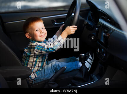 Carino piccolo ragazzo sorridente e padri di guida auto Foto Stock