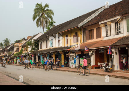 Gruppo di occidentale i turisti in bicicletta sulla strada Sisavangvong a Luang Prabang, Laos. Foto Stock