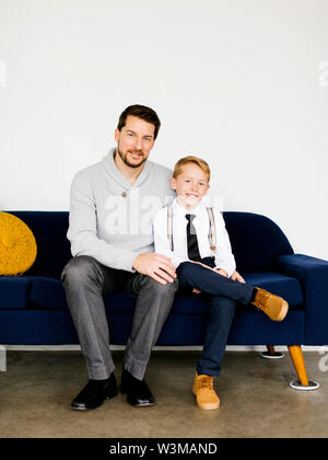 Sorridente padre e figlio seduti sul divano Foto Stock