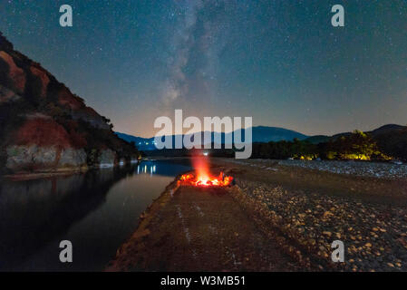 La Via Lattea accanto al fuoco sul fiume Foto Stock