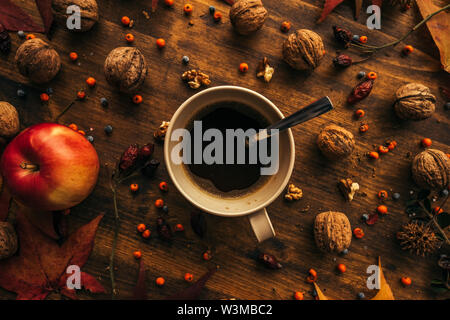 Autunno pausa caffè, tazza di una bevanda calda visto direttamente sopra con la stagione autunnale di frutta e foglie secche Foto Stock