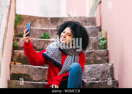 Giovane donna prendendo selfie sui passi Foto Stock