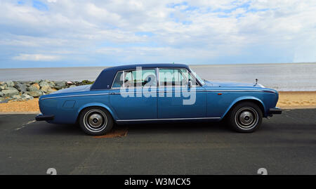 Blu classico Rolls Royce automobile parcheggiata sul lungomare con spiaggia e mare sullo sfondo. Foto Stock